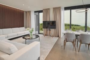 Petram Resort & Residences في سافودريا: غرفة معيشة مع أريكة بيضاء وطاولة