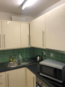 uma cozinha com armários brancos, um lavatório e um micro-ondas em Hotel 63 em Londres