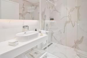 a white bathroom with a sink and a shower at Petram Resort & Residences in Savudrija