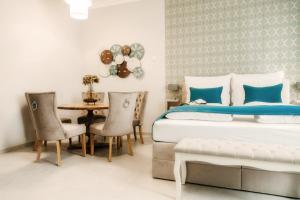 a bedroom with a bed and a table and chairs at Ella Sun Apartman in Makó