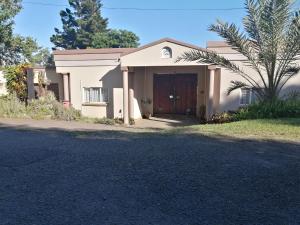 una pequeña casa blanca con una puerta grande en Serendipity Country House en Amanzimtoti