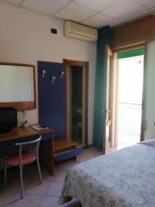 1 dormitorio con 1 cama, escritorio y TV en Hotel Trifoglio, en Lido di Jesolo