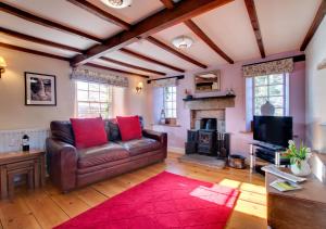 a living room with a leather couch and a fireplace at Rooks Cottage in Askrigg