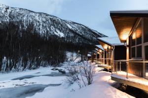 a cabin in the snow next to a river at Tromsø Lodge & Camping in Tromsø