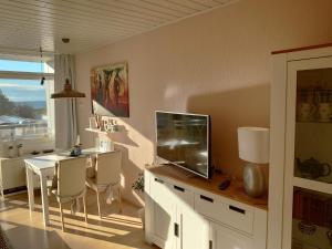 ein Wohnzimmer mit einem Schreibtisch, einem TV und einem Tisch mit Stühlen in der Unterkunft "Mit Ausblick"-uneingeschränkter Meerblick in Burgtiefe auf Fehmarn 