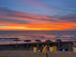 - un coucher de soleil sur la plage avec des chaises et des parasols dans l'établissement Romantic Palace Beach Apartments, à Agios Gordios