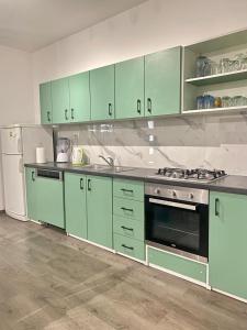 La cuisine est équipée d'armoires vertes, d'une cuisinière et d'un réfrigérateur. dans l'établissement Two Stars Apartment, à Podstrana