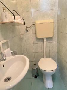 La salle de bains est pourvue de toilettes blanches et d'un lavabo. dans l'établissement Two Stars Apartment, à Podstrana