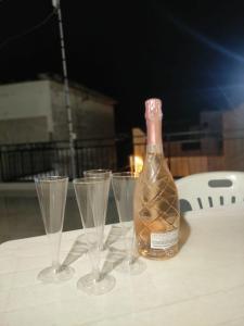 - une bouteille de vin et trois verres à vin sur une table dans l'établissement Affittacamere Girasole, à Modugno