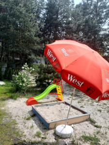 a red umbrella and a playground in the sand at Дом в лесу на берегу Днепра для отдыха, аппартоменты in Budishche