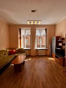 a living room with a couch and a table and two windows at Apartaments near Ploshcha Rynok in Lviv