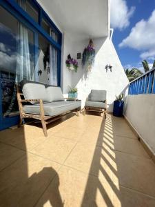 a patio with a couch and chairs on a balcony at Casita Mara! 2’ Line to the sea, shops and bar’s in Puerto del Carmen