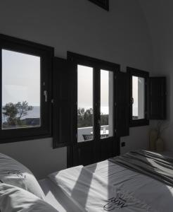 1 dormitorio con 2 camas y 3 ventanas en AKRI Suites Vourvoulos en Vourvoúlos