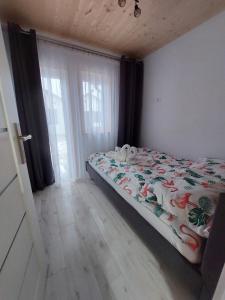 a bedroom with a bed with a comforter and a window at Domki Letniskowe Family Dreams in Sarbinowo