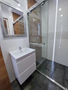 a white bathroom with a sink and a shower at Domki Letniskowe Family Dreams in Sarbinowo