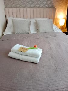 a bed with a towel and a flower on it at Apartament Glamour Chełm in Chełm