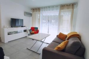 een woonkamer met een bank, een tafel en een tv bij Centre Cannes Martinez, Beau F2 avec terrasse in Cannes