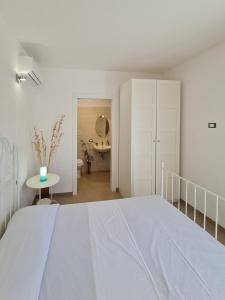 Dormitorio blanco con cama y mesa en Villa Occidente - Homelike Villas, en Castellammare del Golfo