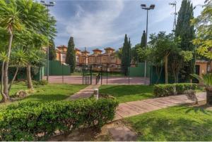 un parque con palmeras y un edificio en Pinares de Lepe, en Huelva