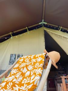 a bed in a tent with a hat on it at Tentes Safari aux Gîtes de Cormenin in Saint-Hilaire-sur-Puiseaux
