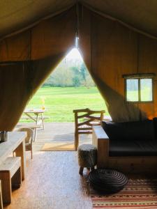 Blick auf einen Raum mit Couch und Tischen in der Unterkunft Tentes Safari aux Gîtes de Cormenin in Saint-Hilaire-sur-Puiseaux