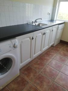 a kitchen with a sink and a washing machine at Cozy 6 Bedroom house with spectacular views in Belmullet