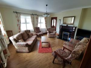 a living room with couches and chairs and a fireplace at Cozy 6 Bedroom house with spectacular views in Belmullet