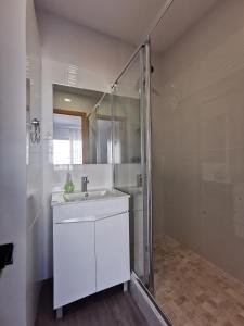 a white bathroom with a sink and a shower at Vila Alexandra in Costa da Caparica