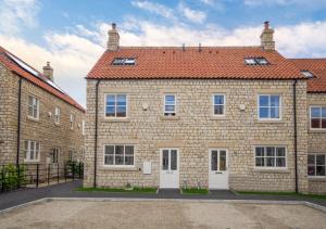 una gran casa de ladrillo con techo rojo en Pinfold Cottage, en Helmsley