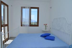 1 dormitorio con 1 cama azul y 2 almohadas azules en Villa Occidente - Homelike Villas, en Castellammare del Golfo