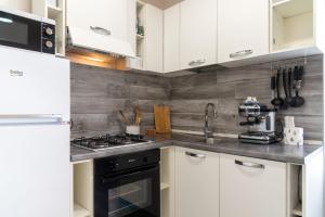 una cucina con armadi bianchi e un forno a piano cottura nero di Appartamento Moderno Capoliveri a Capoliveri