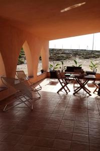 eine Gruppe von Stühlen und Tischen in einem Gebäude in der Unterkunft Relax e tranquillità a Cala Pisana in Lampedusa
