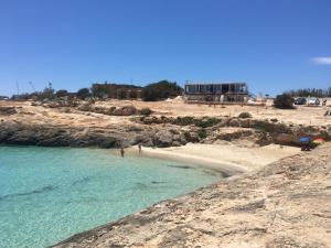 a beach with people standing on the sand and the water at Relax e tranquillità a Cala Pisana in Lampedusa