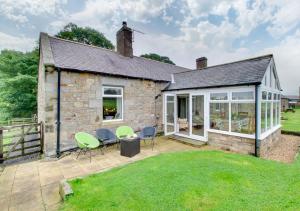 an external view of a stone house with a patio at Burn Bank Cottage in Belford