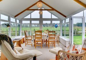 a conservatory with a dining room with a table and chairs at Burn Bank Cottage in Belford