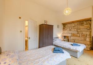 a bedroom with two beds and a stone wall at Vale View in Glanton