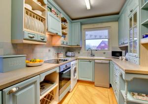 uma cozinha com armários azuis e um lavatório em Dunes Reach 3 Dunes Court em Beadnell