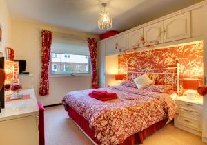 um quarto com uma cama com uma colcha vermelha em Dunes Reach 3 Dunes Court em Beadnell