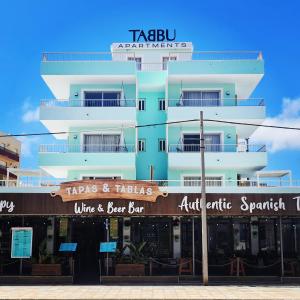 a tall white building with a sign on it at Tabbu ibiza apartments in Playa d'en Bossa