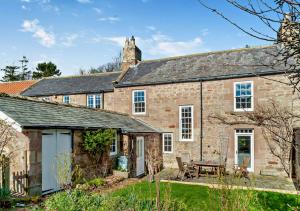 an old stone house with a picnic table in the yard at Glebe Farmhouse in Ellingham