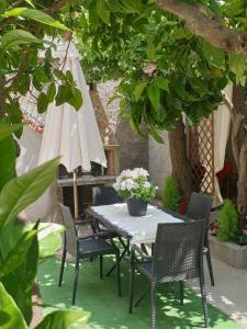 una mesa y sillas bajo un árbol con sombrilla en Casa vacanze con giardino e area barbecue en Martis