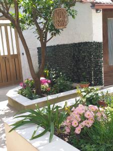 un jardín con flores y un árbol frente a un edificio en Casa vacanze con giardino e area barbecue, en Martis