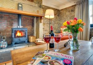 a table with two glasses of wine and a fireplace at Pegasus Cottage in Craster