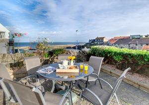 a table and chairs on a patio with a view of the ocean at Pegasus Cottage in Craster