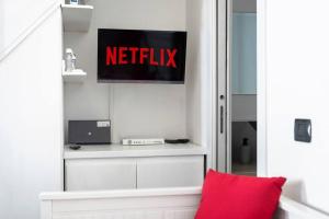 una habitación con una señal de netflix y una almohada roja en Sorres Home & Relax 10 min da Sassari Loft AC e WiFi, en Codrongianos