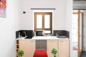 cocina con encimera y silla roja en Sorres Home & Relax 10 min da Sassari Loft AC e WiFi, en Codrongianos