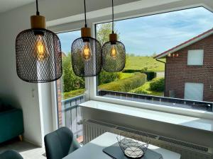 a room with a large window with three lights at Ferienwohnung Deichblick - Haus Seeschwalbe in Wangerland