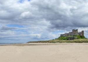 a castle sitting on top of a hill next to a beach at Greenleaf in Bamburgh