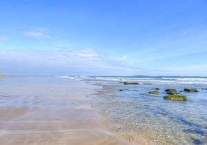 a beach with some rocks in the water at The Greenhouse in Bamburgh