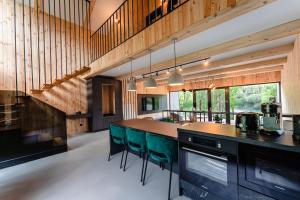 a kitchen with wooden walls and a counter with green chairs at Vila ZIA in Teşila